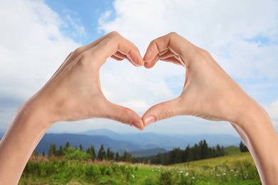 Image of Woman making heart with hands outdoors on sunny day, closeup