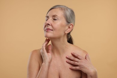 Photo of Beautiful woman touching her neck on beige background