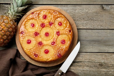 Photo of Tasty pineapple cake with cherries on wooden table, flat lay. Space for text