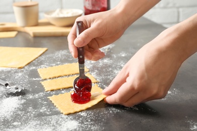 Photo of Young woman preparing ravioli with jam at table. Delicious pasta