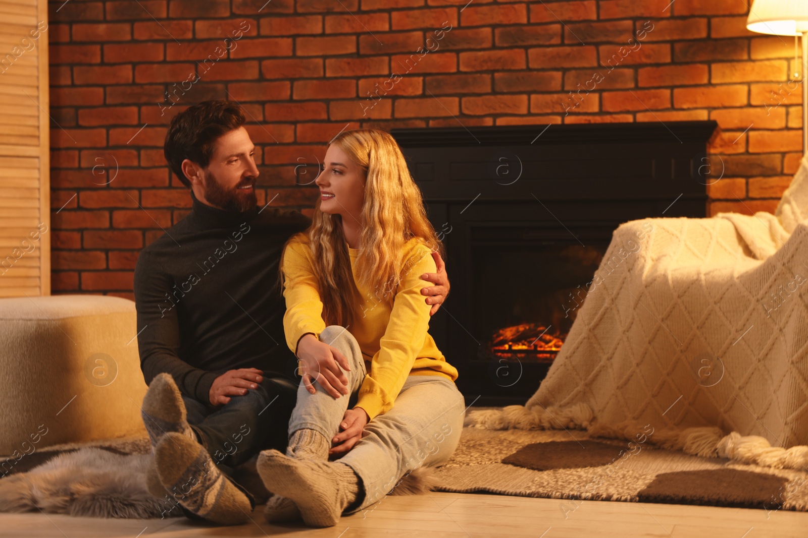 Photo of Lovely couple spending time together near fireplace in room