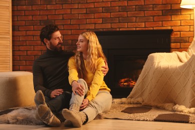 Lovely couple spending time together near fireplace in room