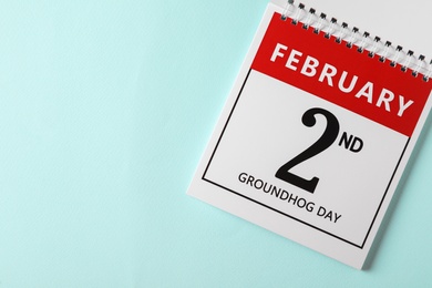 Photo of Top view of calendar with date February 2nd on light blue background, space for text. Groundhog day
