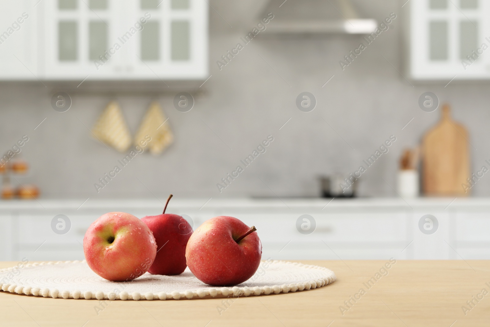 Photo of Fresh ripe apples on wooden table in kitchen, space for text