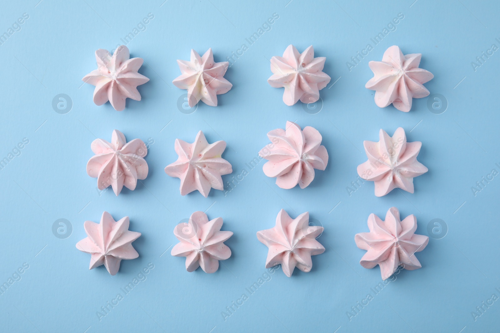 Photo of Tasty meringue cookies on light blue background, flat lay