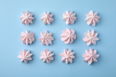 Tasty meringue cookies on light blue background, flat lay