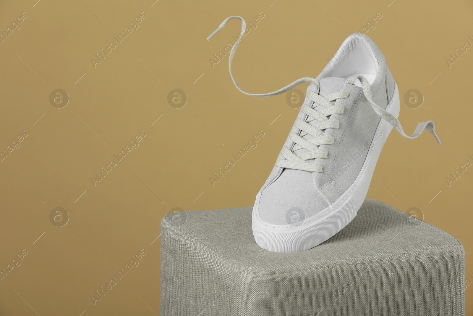 Photo of Stylish presentation of trendy sneaker on beige background. Space for text