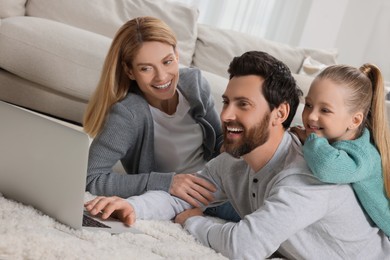 Photo of Happy family with laptop on floor at home