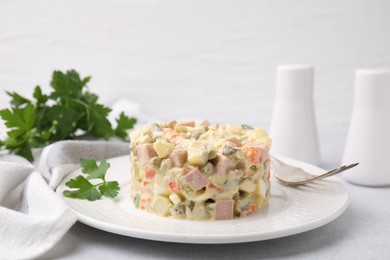 Photo of Tasty Olivier salad with boiled sausage and fork on light table, closeup