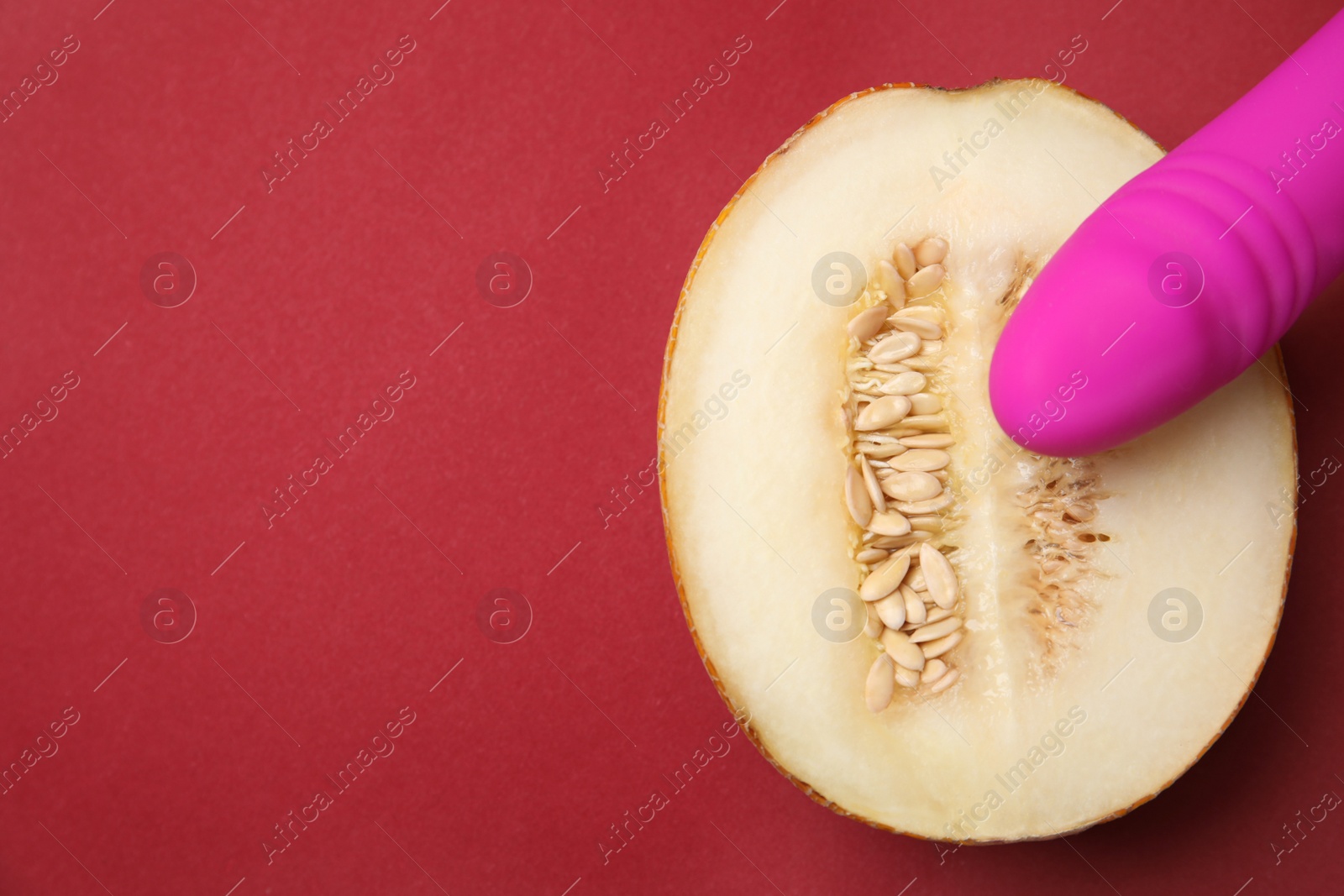 Photo of Half of melon and purple vibrator on red background, flat lay with space for text. Sex concept