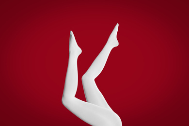 Woman wearing white tights on red background, closeup of legs
