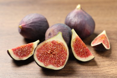 Photo of Whole and cut ripe figs on wooden table, closeup