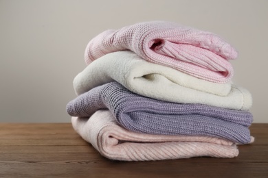 Photo of Stack of knitted sweaters on wooden table