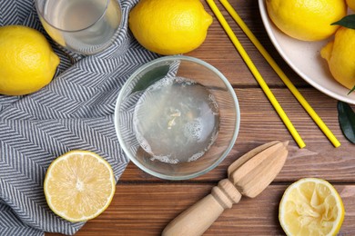 Photo of Citrus reamer, juice and fresh lemons on wooden table, flat lay
