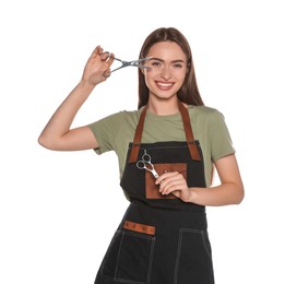 Photo of Portrait of happy hairdresser with professional scissors on white background