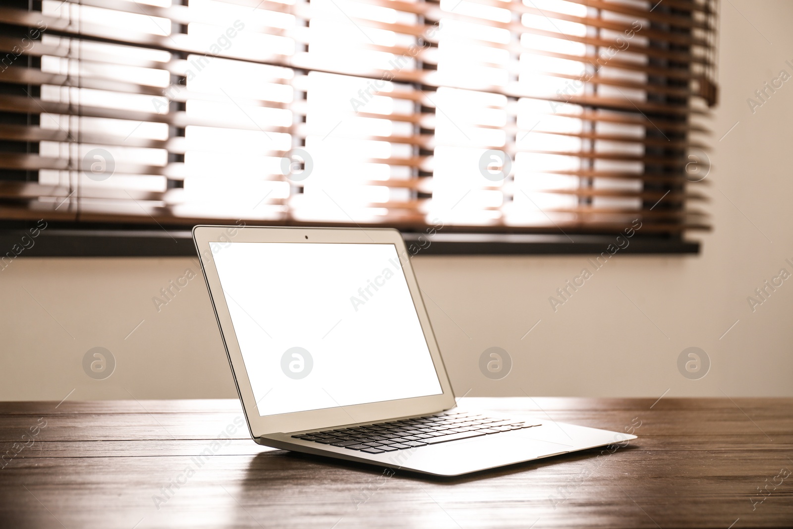 Photo of Modern laptop with blank screen on table in room