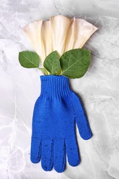 Photo of Gardening gloves with beautiful flowers on light grey marble table, top view