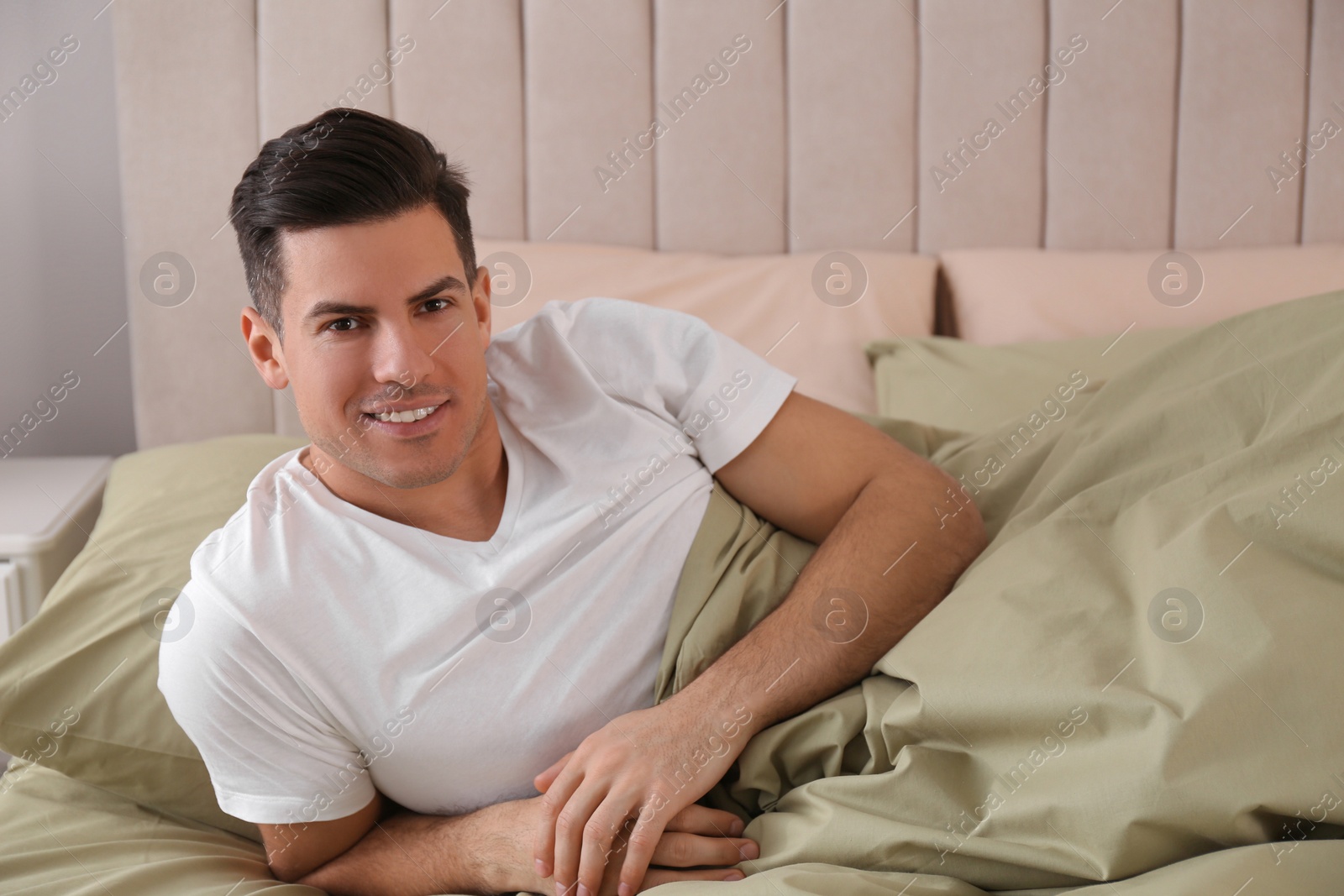 Photo of Man lying in comfortable bed with green linens