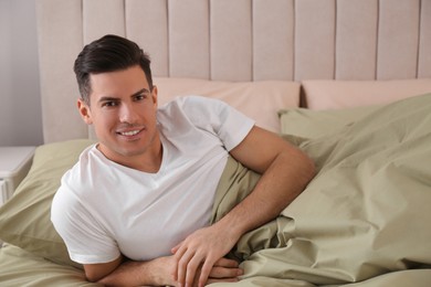 Photo of Man lying in comfortable bed with green linens