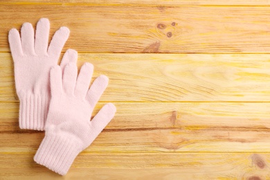 Stylish pink gloves on wooden background, flat lay. Space for text