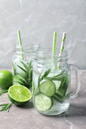 Photo of Natural lemonade with cucumber, lime and rosemary in mason jars on table