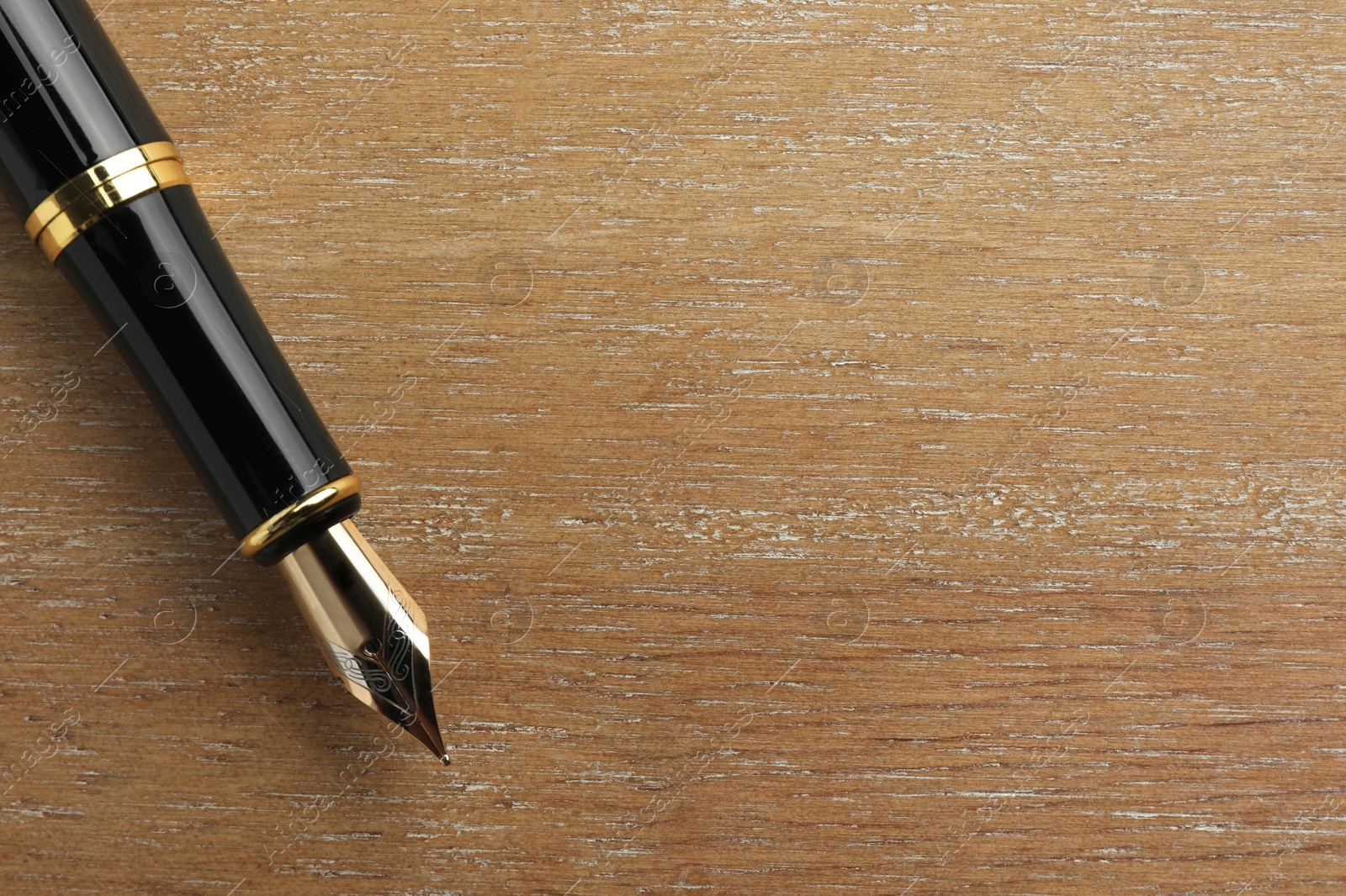 Photo of Stylish fountain pen on wooden table, top view. Space for text