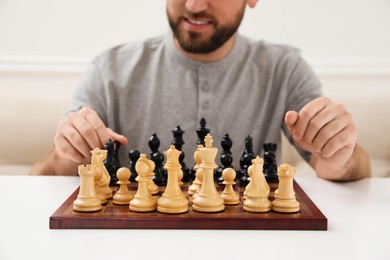Photo of Man playing chess at white table indoors, closeup