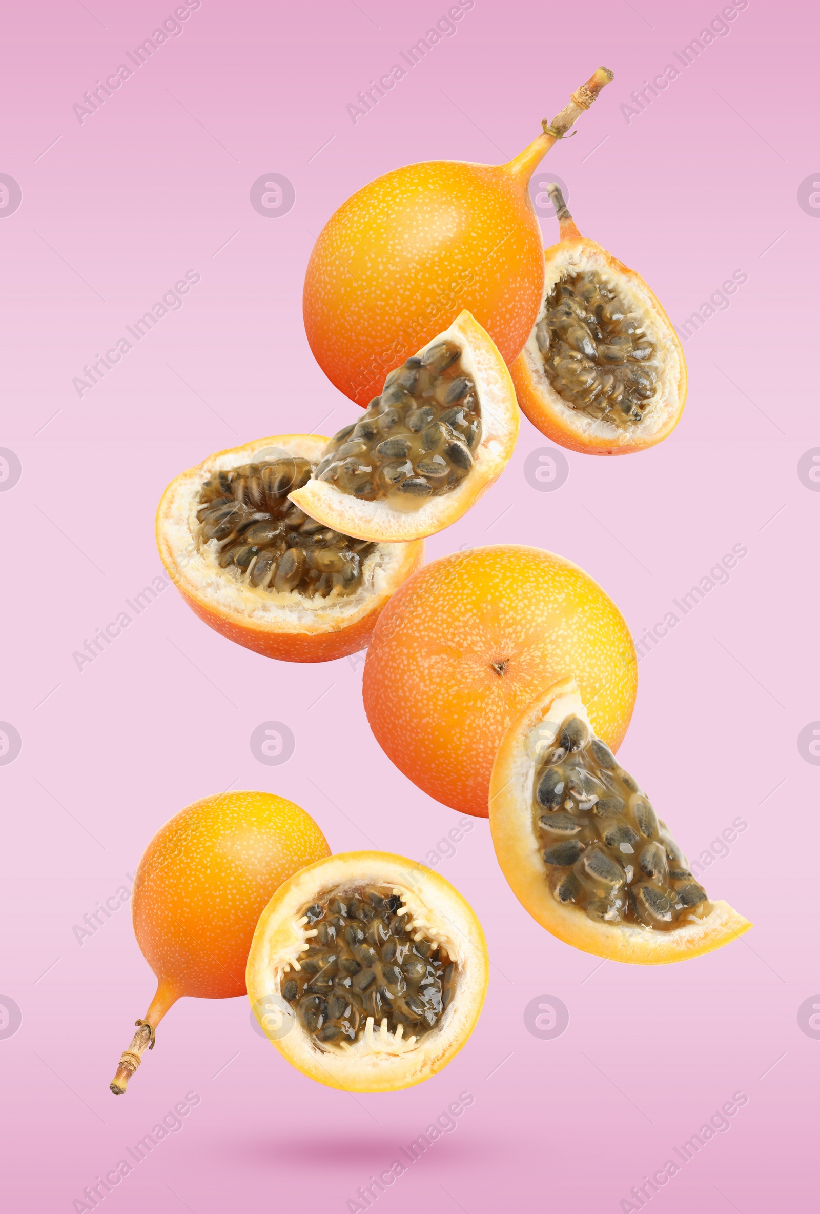 Image of Delicious ripe granadillas falling on violet background