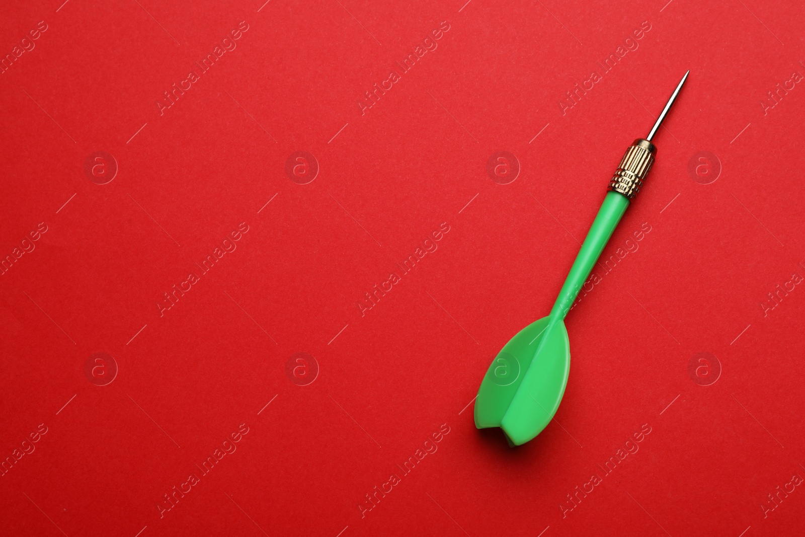 Photo of Green dart arrow on red background, top view with space for text