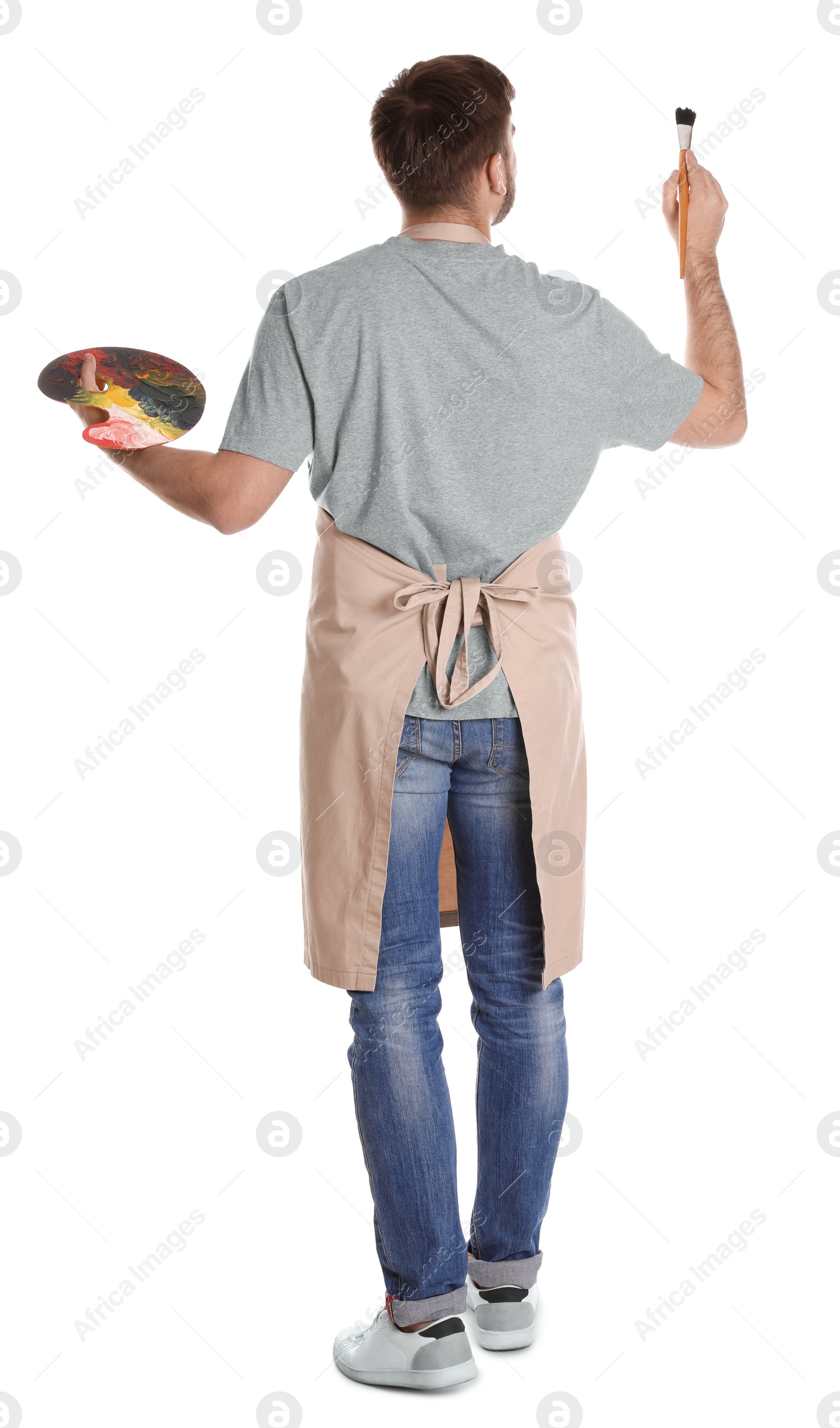 Photo of Man painting with brush on white background, back view. Young artist