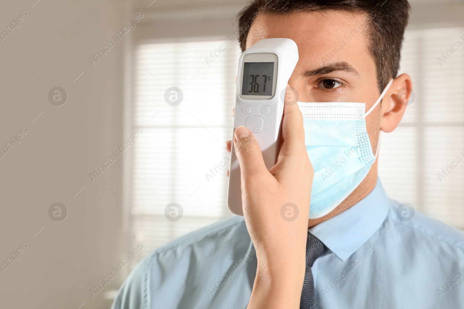 Photo of Doctor measuring man's temperature in office closeup. Prevent spreading of Covid-19