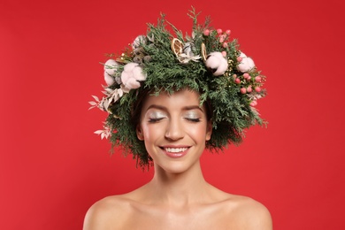 Photo of Happy young woman wearing wreath on red background