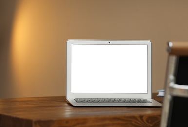 Photo of Laptop with blank screen on table indoors. Space for text