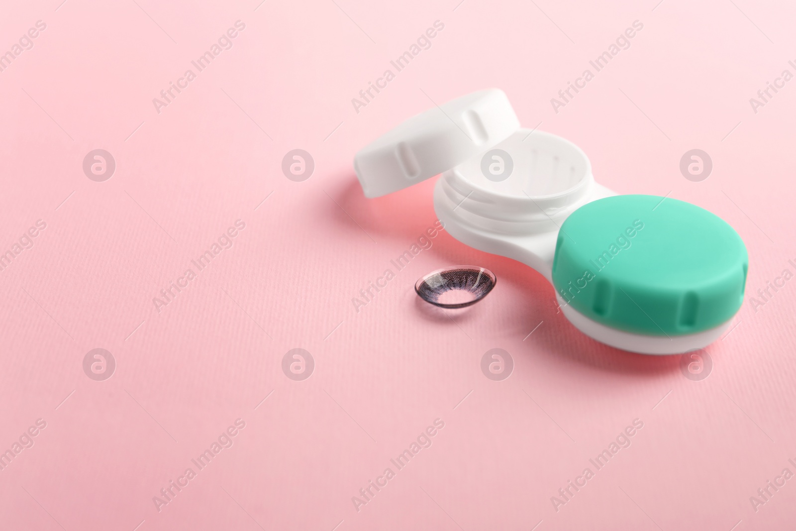 Photo of Case with color contact lenses on pink background. Space for text