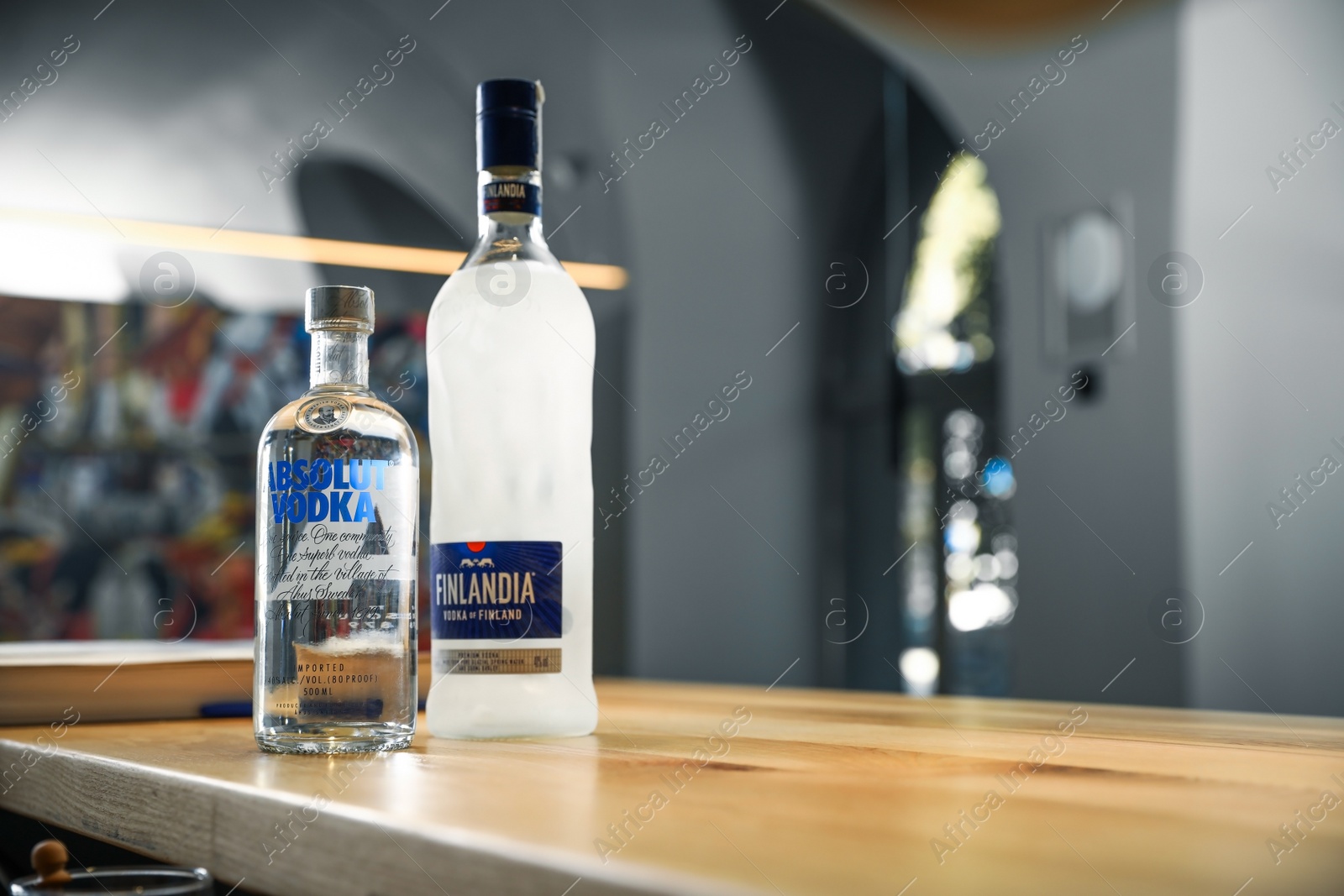 Photo of MYKOLAIV, UKRAINE - SEPTEMBER 23, 2019: Bottles of Finlandia and Absolut vodka on wooden counter in bar