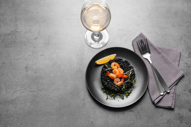 Photo of Delicious black risotto with shrimps served on grey table, flat lay. Space for text