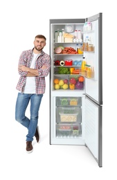 Photo of Young man near open refrigerator on white background