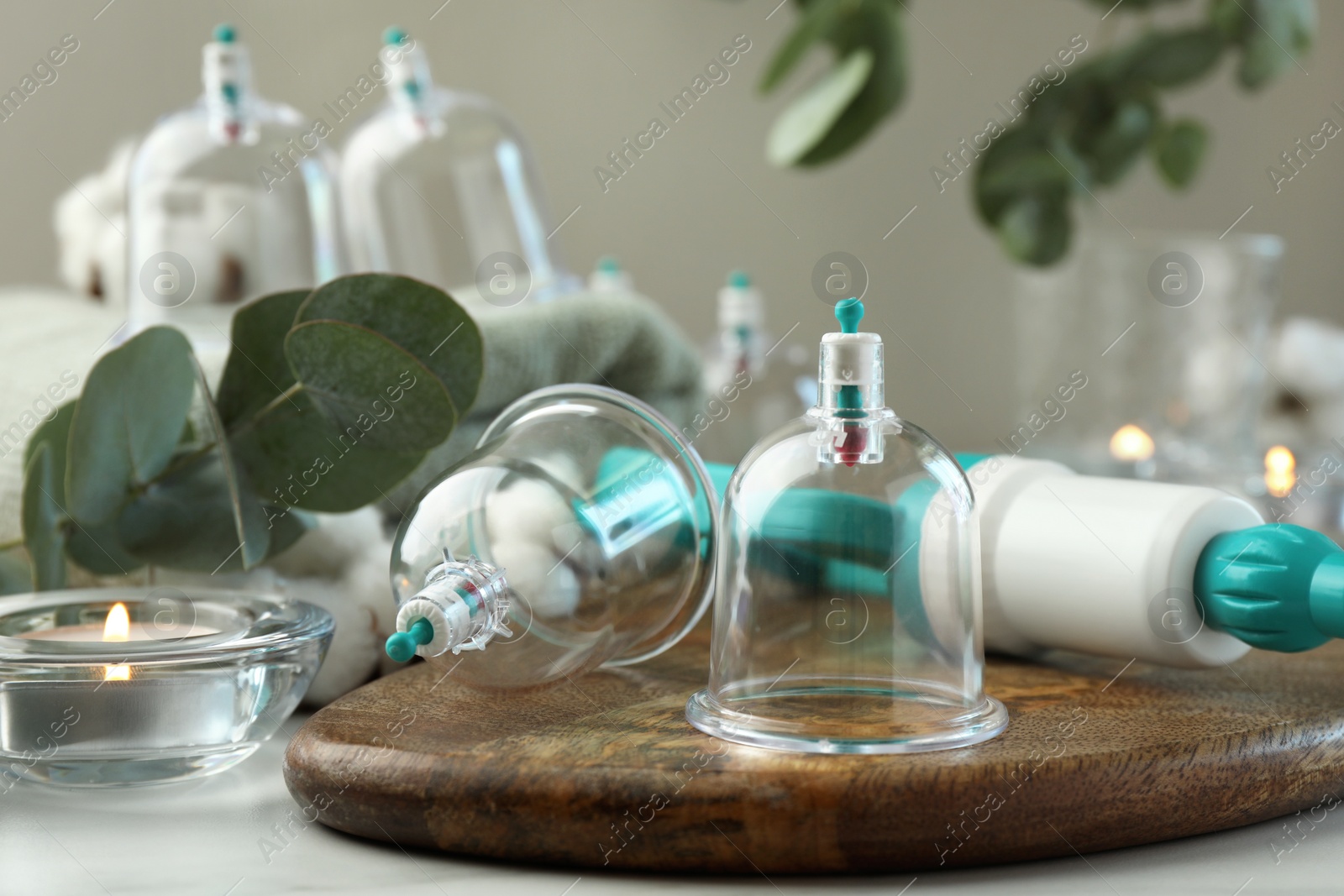 Photo of Plastic cups and hand pump on white table. Cupping therapy