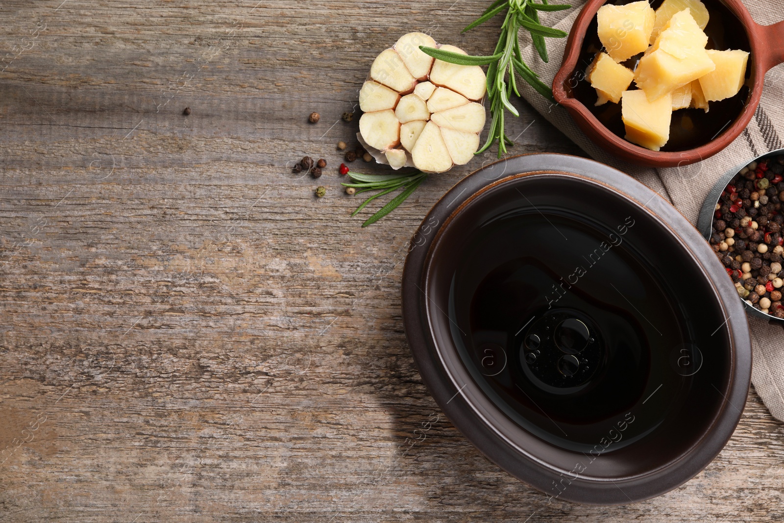 Photo of Bowl of balsamic vinegar with oil, parmesan cheese, garlic and spices on wooden table, flat lay. Space for text