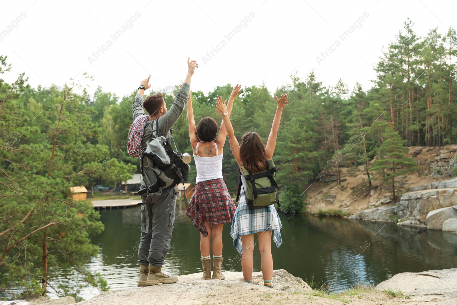 Photo of Young friends on rocky mountain near lake. Camping season