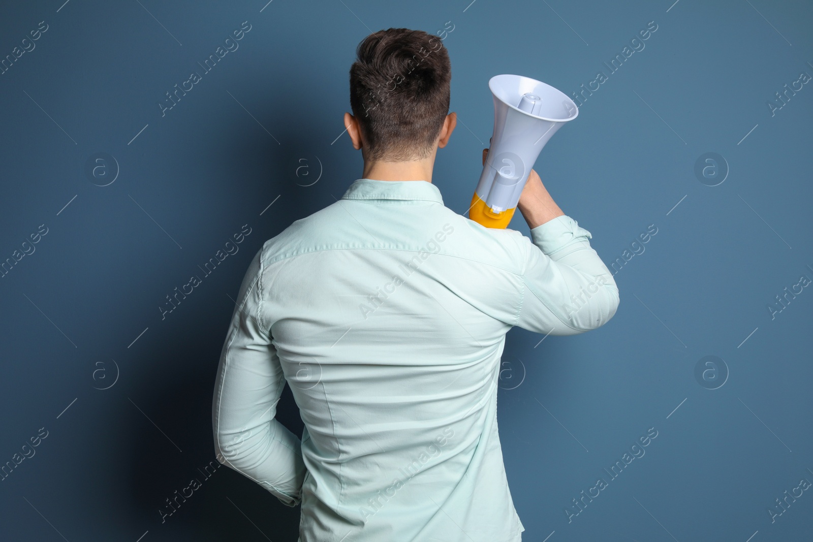 Photo of Young man with megaphone on color background