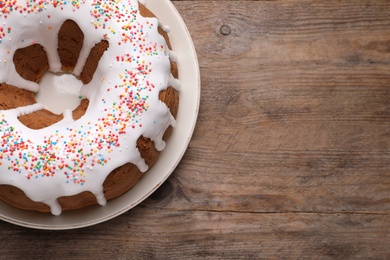 Glazed Easter cake with sprinkles on wooden table, top view. Space for text