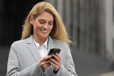 Photo of Smiling woman with smartphone outdoors, space for text. Lawyer, businesswoman, accountant or manager