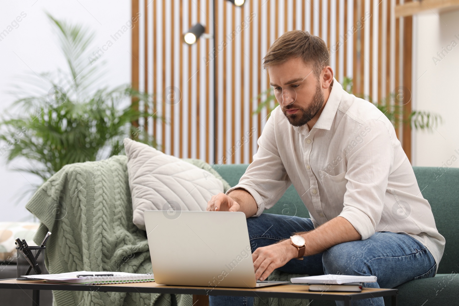 Photo of Young man working with laptop at home, space for text