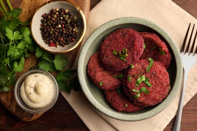 Photo of Tasty vegan cutlets with sauce and ingredients on wooden table, flat lay
