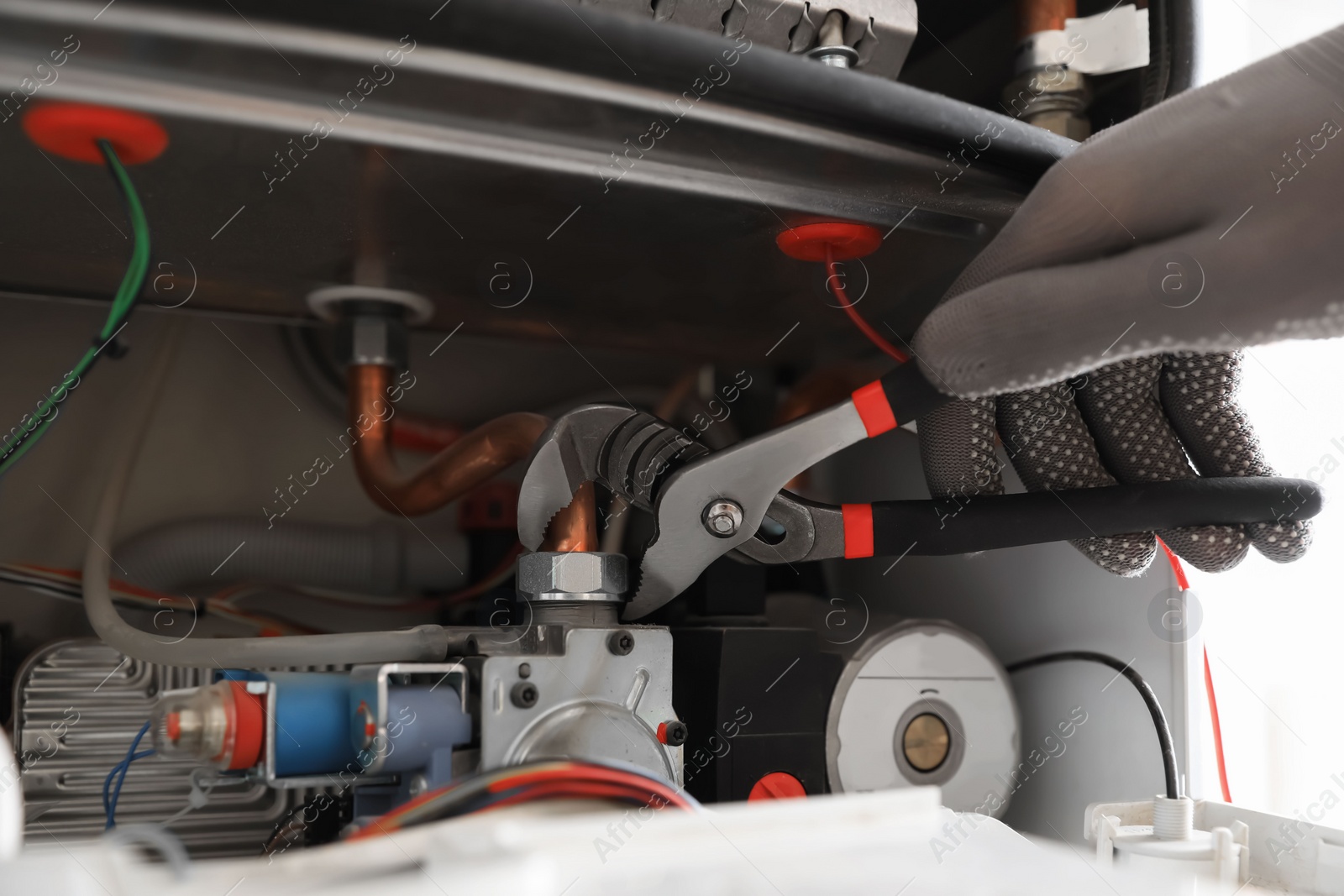 Photo of Man repairing gas boiler with waterpump plier, closeup