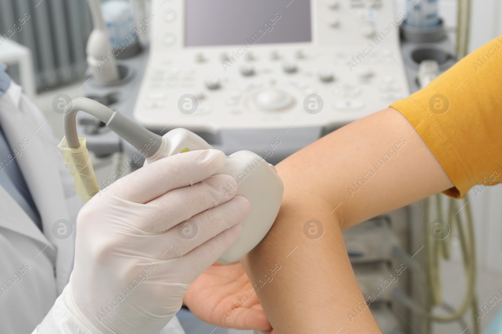 Photo of Doctor conducting ultrasound examination of patient's elbow in clinic, closeup