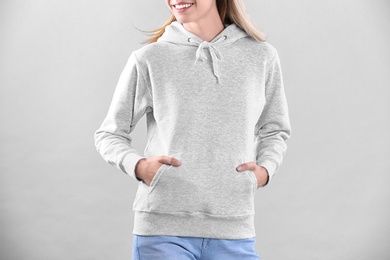 Woman in hoodie sweater on light background. Space for design