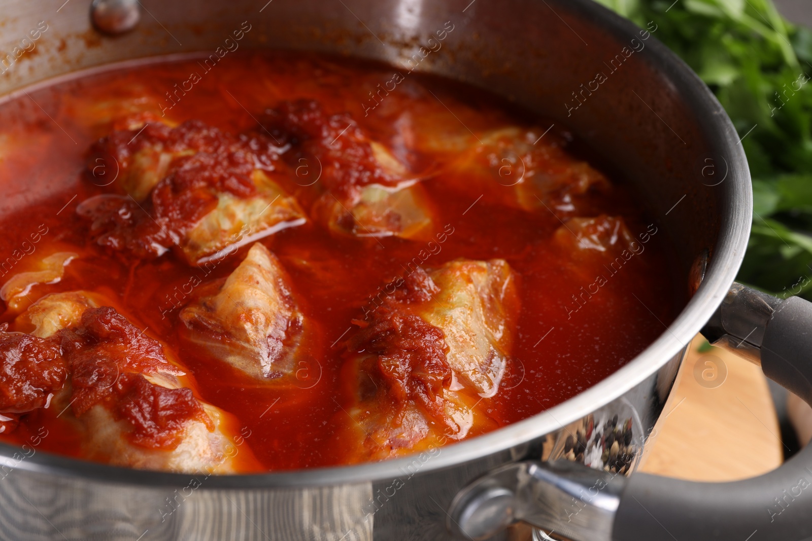 Photo of Delicious stuffed cabbage rolls cooked with homemade tomato sauce in pot, closeup