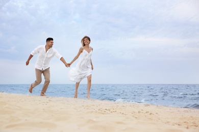 Photo of Happy couple running on beach, space for text. Romantic walk